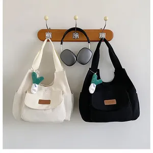 Detail of canvas tote bags with leather fashion tags and plush green vegetable charms
