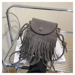 Détail du sac bandoulière en daim gris avec de longues franges et sangle à nœuds