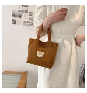 Detail of brown corduroy tote bag featuring a cute teddy bear embroidery with snap button