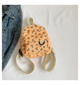 Detailed macro view of orange corduroy mini backpack featuring cute cherry prints and straps