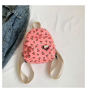 Detailed macro view of pink corduroy mini backpack with red cherry prints and front pocket