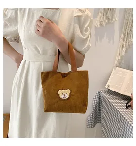 Detailed macro view of a brown corduroy mini tote bag with a cute teddy bear patch