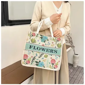 Detail of floral woven tote bag with FLOWERS text and pink roses on canvas fabric