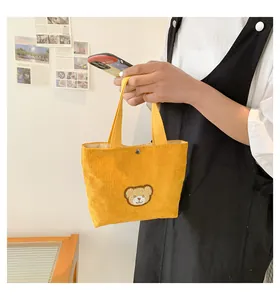 Detail of yellow corduroy mini tote bag with cute brown bear embroidery and metal snap