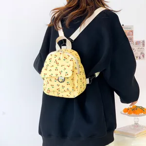 Mini yellow corduroy backpack with cherry print shown on a model against a white wall