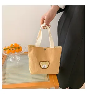 Macro shot of yellow corduroy handbag fabric and cute teddy bear embroidery detail