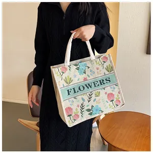 Detailed close-up of large canvas tote bag with floral embroidery and flowers text