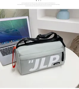 Detail of grey nylon messenger bag with JLP logo and red decorative loop on white desk