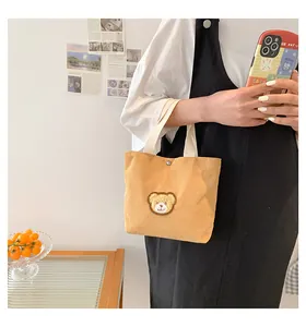 Detail view of mini yellow corduroy handbag with a cute teddy bear patch for women