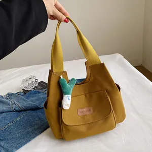 Minimalist mustard yellow canvas tote bag with front pocket and plush green charm