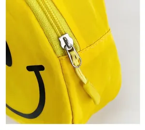 Détail de la fermeture éclair argentée et smiley noir sur le sac en nylon jaune enfant