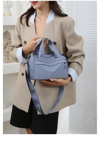 Borsa a tracolla in nylon blu indossata da una modella in un interno moderno minimalista