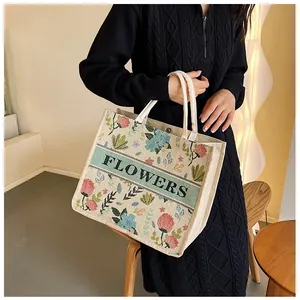 Close-up of floral embroidery on linen tote bag with green FLOWERS ribbon detail