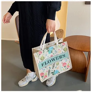 Detailed close-up of floral embroidery and FLOWERS lettering on beige linen tote bag