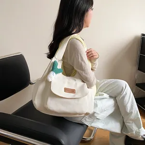 Minimalist white canvas tote bag for women with leather tag and green plush pendant