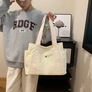 Minimalist beige canvas tote bag with metal buckle pocket and wide shoulder straps
