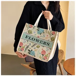 Close-up of vintage floral embroidery and green 'FLOWERS' band on a linen tote bag