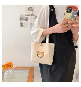 Detailed view of cream corduroy tote bag featuring a cute bear embroidery and metal clasp