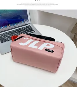 Close-up of pink rectangular utility bag with JLP logo on white table with laptop