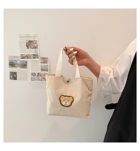 Detail of corduroy mini tote bag in beige with cute brown bear patch and metal snap