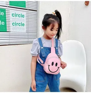 Détail du sac de poitrine en toile rose avec imprimé smiley porté par une fille