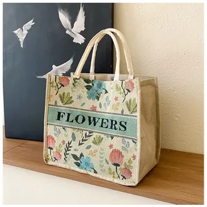 Detail of embroidered floral patterns and 'FLOWERS' text on a vintage linen tote bag