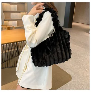 Detail of black plush tote bag with vertical stripes and fluffy pom-pom strap texture