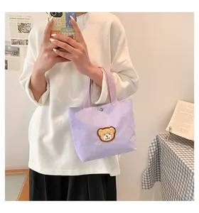 Close-up of a mini light purple corduroy handbag with a cute brown bear patch detail