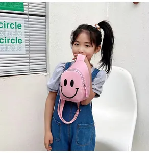 Détail du sac de poitrine rose pour enfant avec motif smiley noir et sangle réglable