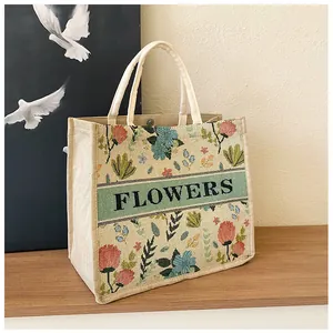 Detail of floral embroidery and FLOWERS text on a linen tote bag with metal snap button