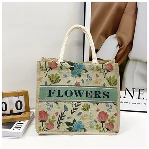Detail of embroidered floral linen tote bag with FLOWERS text and rope handles