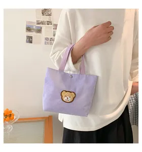 Detailed macro of lavender corduroy handbag with cute brown bear patch and metal clasp