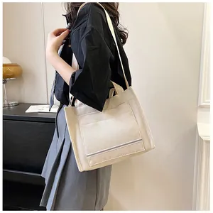 Macro detail of creamy white corduroy tote bag showing front pocket and durable texture