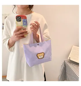 Detail of light purple corduroy mini tote with a cute brown bear embroidery and snap button