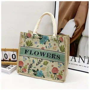 Detail of embroidered floral patterns and FLOWERS text on a woven beige tote bag
