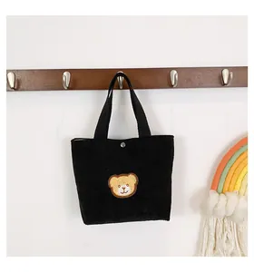 Detail of black corduroy mini tote bag with cute 3D teddy bear patch and metal snap button