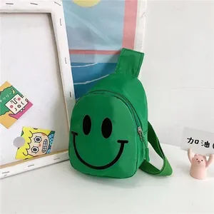 Détail du sac de poitrine vert pour enfants en nylon avec un motif de visage souriant noir