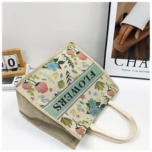 Detailed embroidery of floral patterns and green FLOWERS band on a vintage linen tote bag