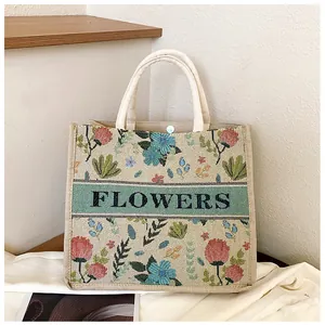 Detail of floral embroidery on linen tote bag with FLOWERS text and snap button