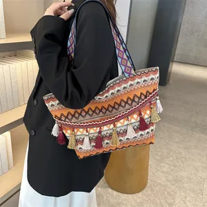 Ethnic style woven tote bag with colorful tassels and wide patterned shoulder strap