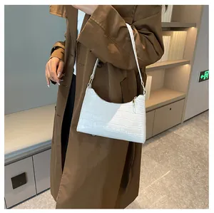 Detail van witte baguette tas met krokodillenpatroon en een gouden ritssluiting