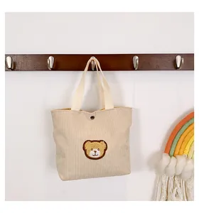 Detail of corduroy handbag with cute bear embroidery and metal snap closure