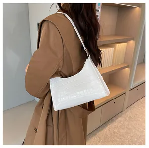 Detail van de witte baguette tas met krokodillenpatroon gedragen bij trenchcoat