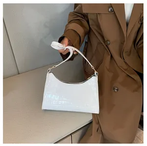 Detail van de witte baguette tas met krokodillenpatroon gedragen door een model