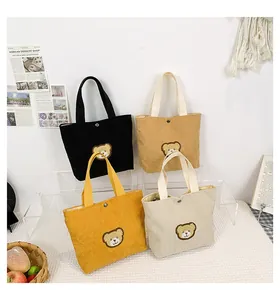 Detail of four colorful corduroy mini tote bags with cute bear embroidery and snap closure