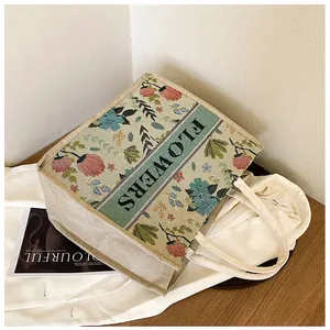 Detailed close-up of beige linen tote bag with floral embroidery and FLOWERS text design