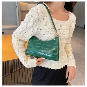 Detail van groene baguette-tas met krokodillenreliëf en bijpassende schouderband