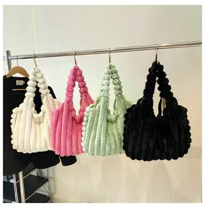Plush tote bags in white pink green and black hanging on a metal rod for display