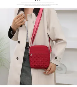 Détail du sac bandoulière rouge avec coutures matelassées et large sangle réglable