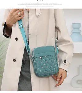 Détail du sac bandoulière matelassé turquoise avec broderies florales blanches en nylon